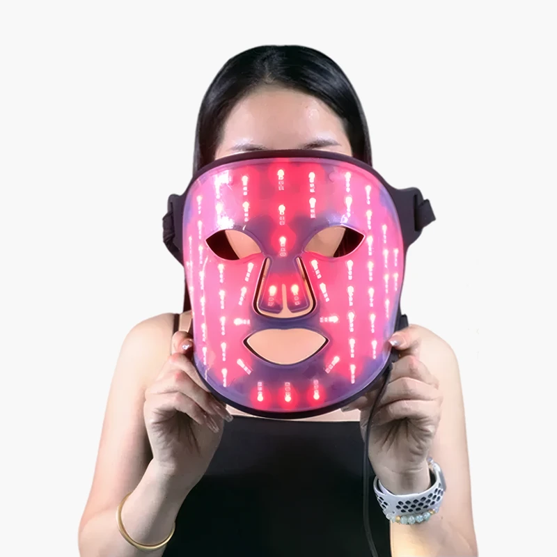 Mujer sosteniendo frente a su rostro la máscara Auren Pro encendida en luz roja.